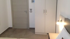 Una habitación con una puerta cerrada, un armario de dos puertas, un interruptor de luz y un enchufe en la pared.