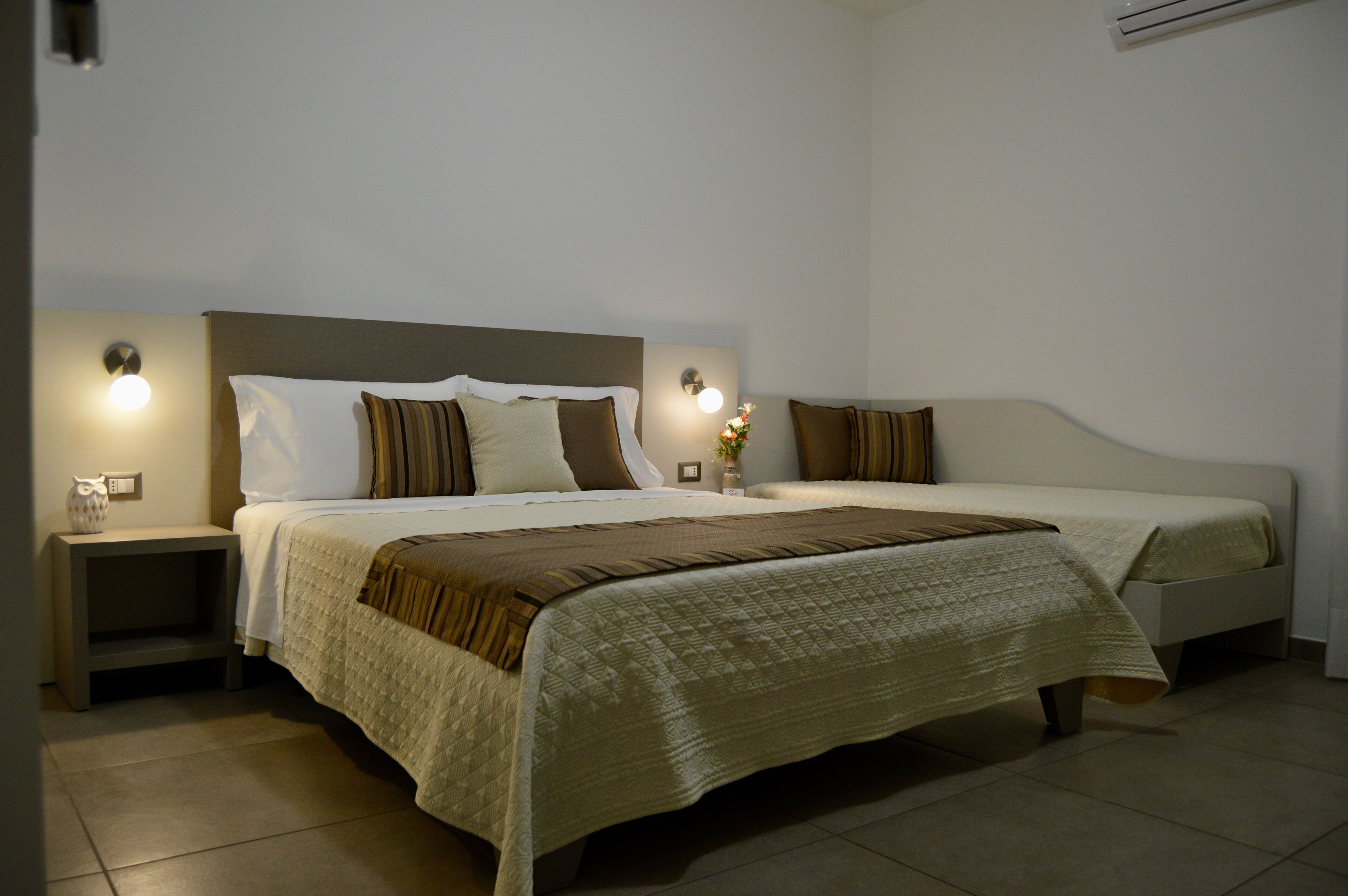 A double bed with a quilted cover, two bedside tables, and wall-mounted lights.