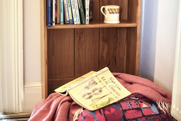 Een boekenplank met boeken en een mok.