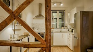 A modern kitchen with white cabinets, a stainless steel refrigerator, and a wooden staircase. - Master Historical Gem in Chiado (Lisboa)