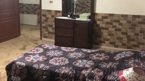 Ein Schlafzimmer mit Bett, Schminktisch, Spiegel und Lampe.