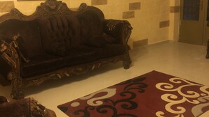 Ein Wohnzimmer mit einem dunkelbraunen Sofa, einem roten und weißen Teppich und einem gerahmten Gemälde an der Wand.