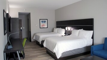 Habitación de hotel con dos camas, un escritorio, una silla, un televisor y un cuadro en la pared.