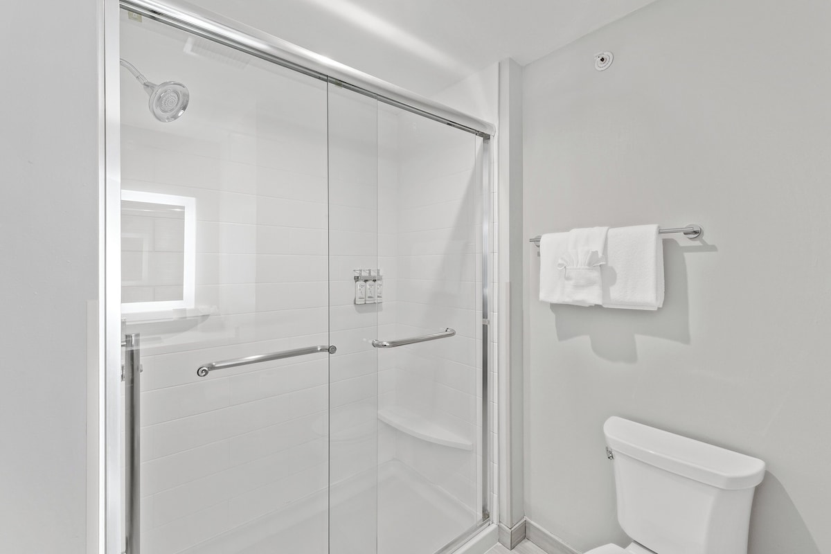Un baño moderno con cabina de ducha de vidrio, inodoro y barra para toallas.