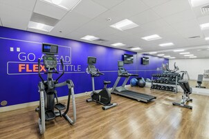 Un gimnasio con cintas de correr, elípticas y máquinas de pesas.
