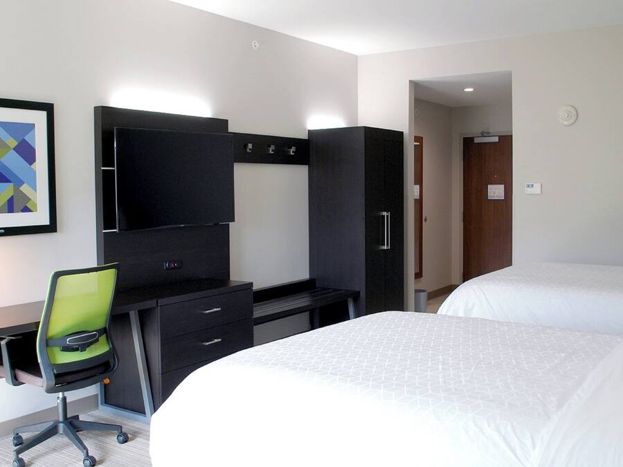 A hotel room with a bed, a desk with a chair, a television, and a wardrobe.