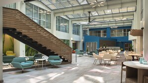 Amplio espacio interior con una escalera moderna, zonas de estar y un techo alto con tragaluces.