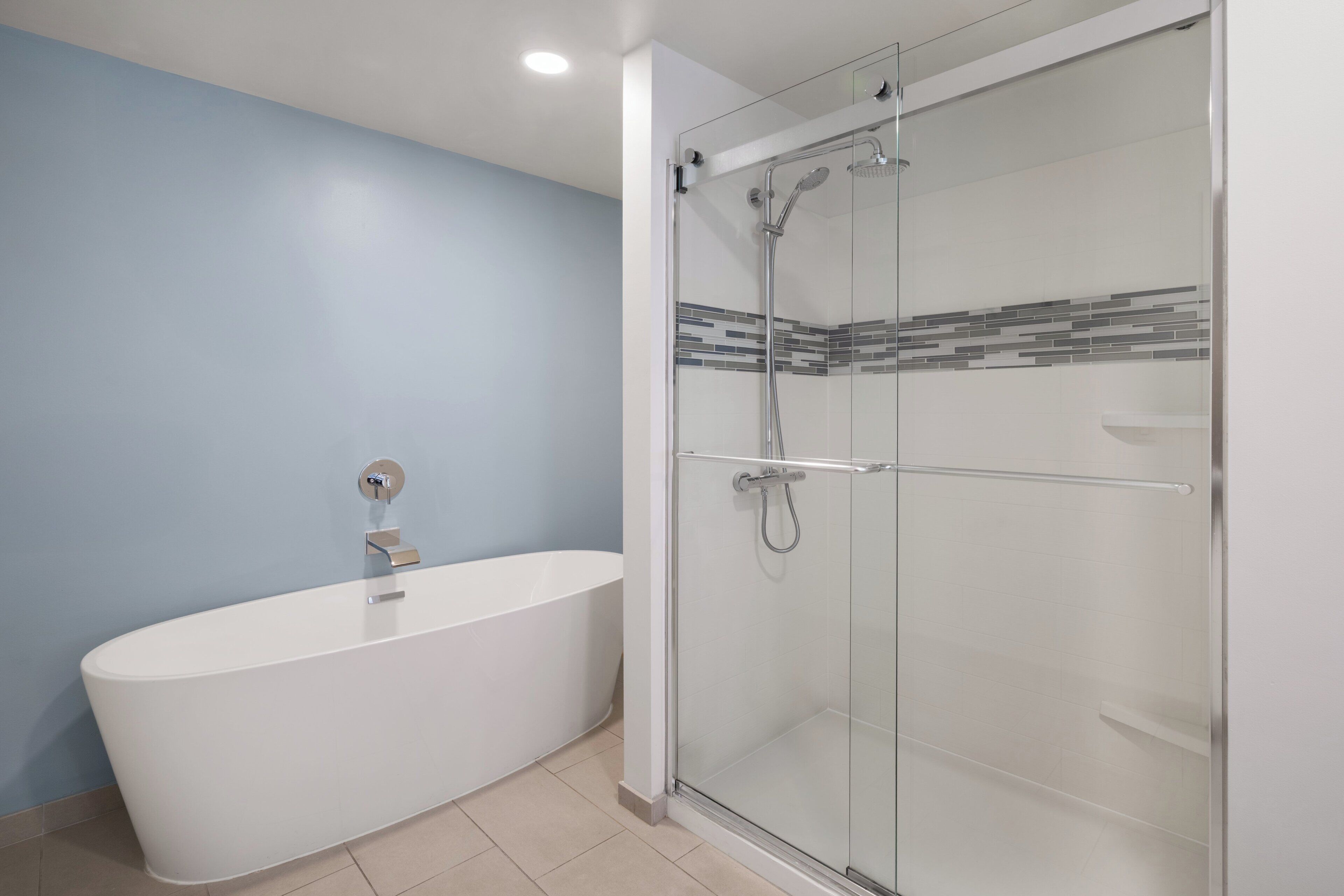 A modern bathroom with a freestanding bathtub, a glass-enclosed shower, and a tiled backsplash.