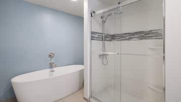A modern bathroom with a freestanding bathtub, a glass-enclosed shower, and a tiled backsplash.
