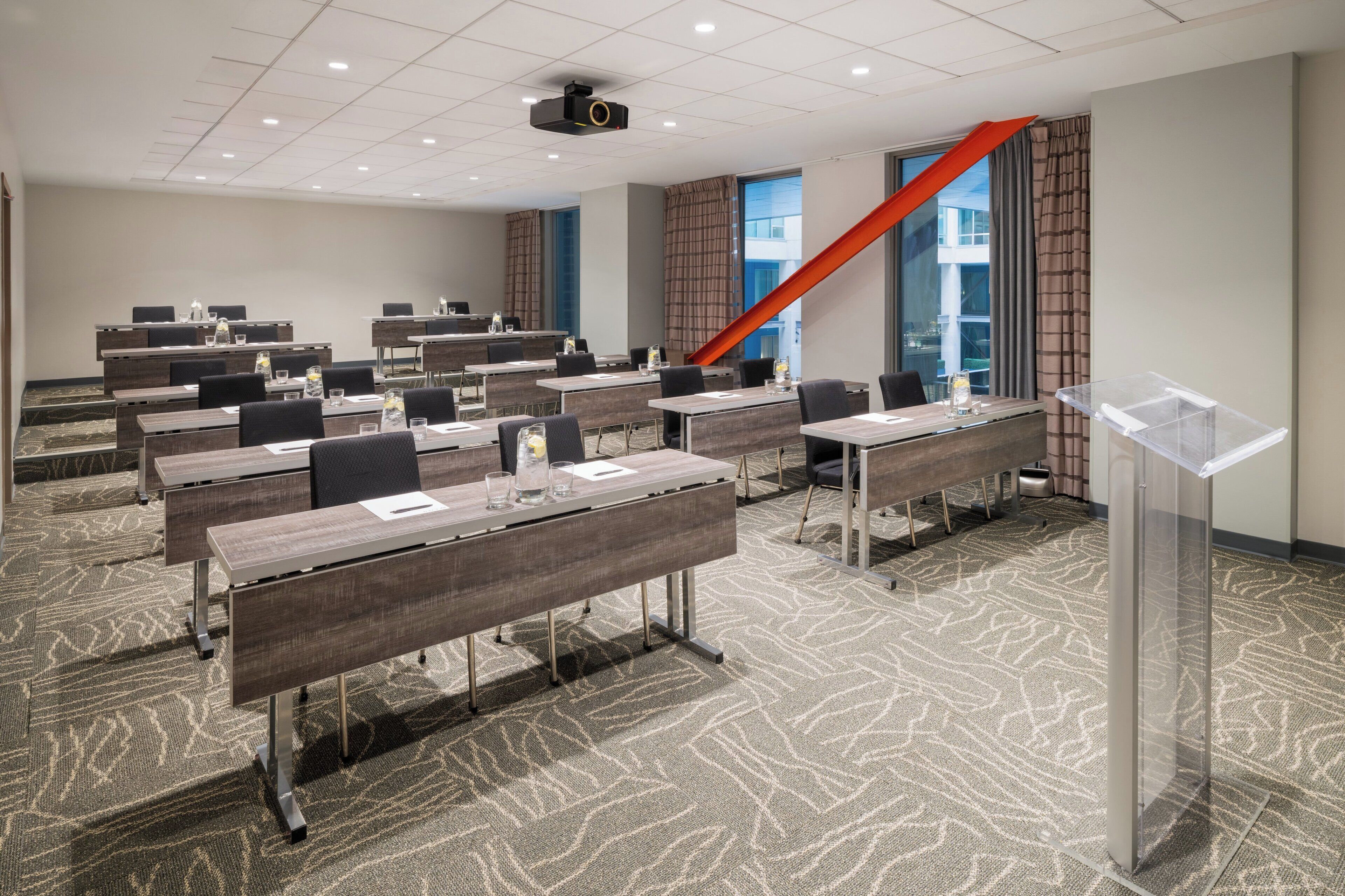 A conference room with multiple tables, chairs, a podium, and a projector.