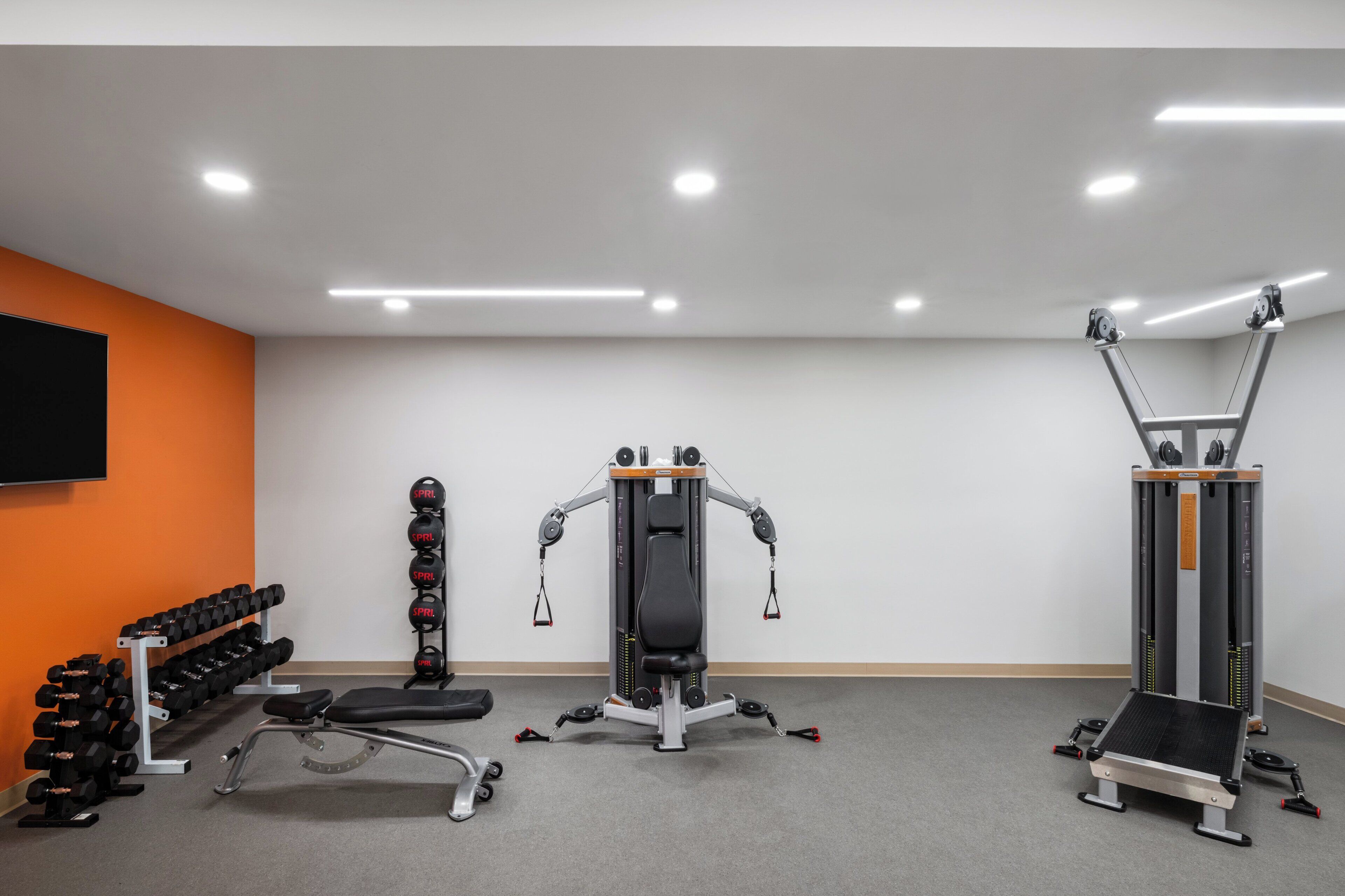 A gym with weight machines, dumbbells, and a bench.