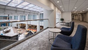 Un espacio interior amplio con techo alto, un entrepiso y una zona central abierta con asientos y mesas.