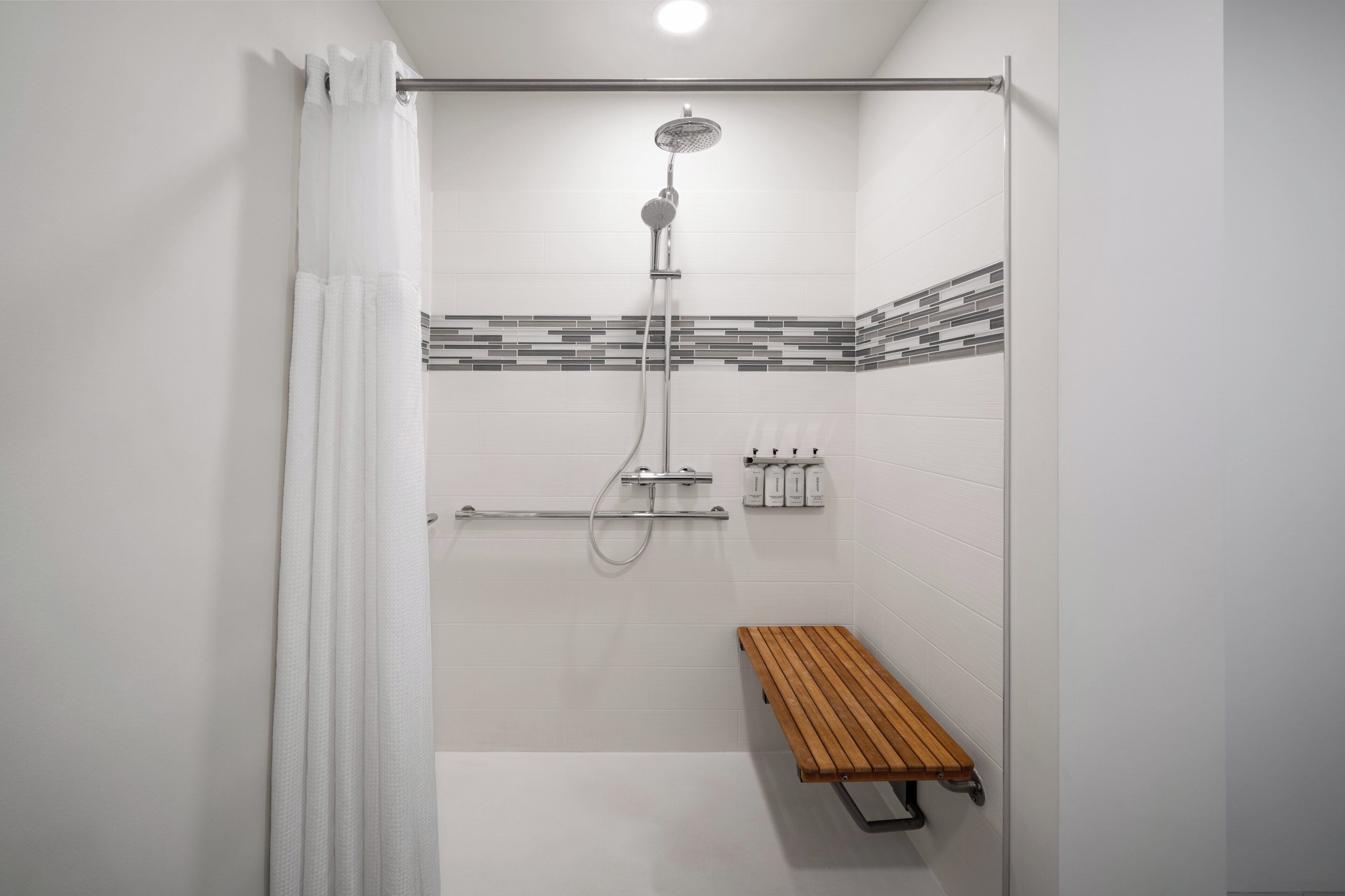 A shower with a rain showerhead, a handheld showerhead, and a handheld shower attachment.