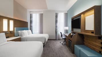 Une chambre d’hôtel avec deux lits, un bureau, une télévision et un coin salon.