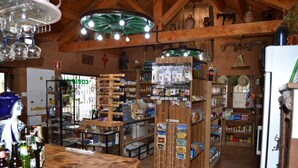 A rustic interior with wooden beams, a variety of shelves stocked with goods, and a display counter with bottles. - El Trasgu de Foncebadón (Santa Colomba de Somoza)