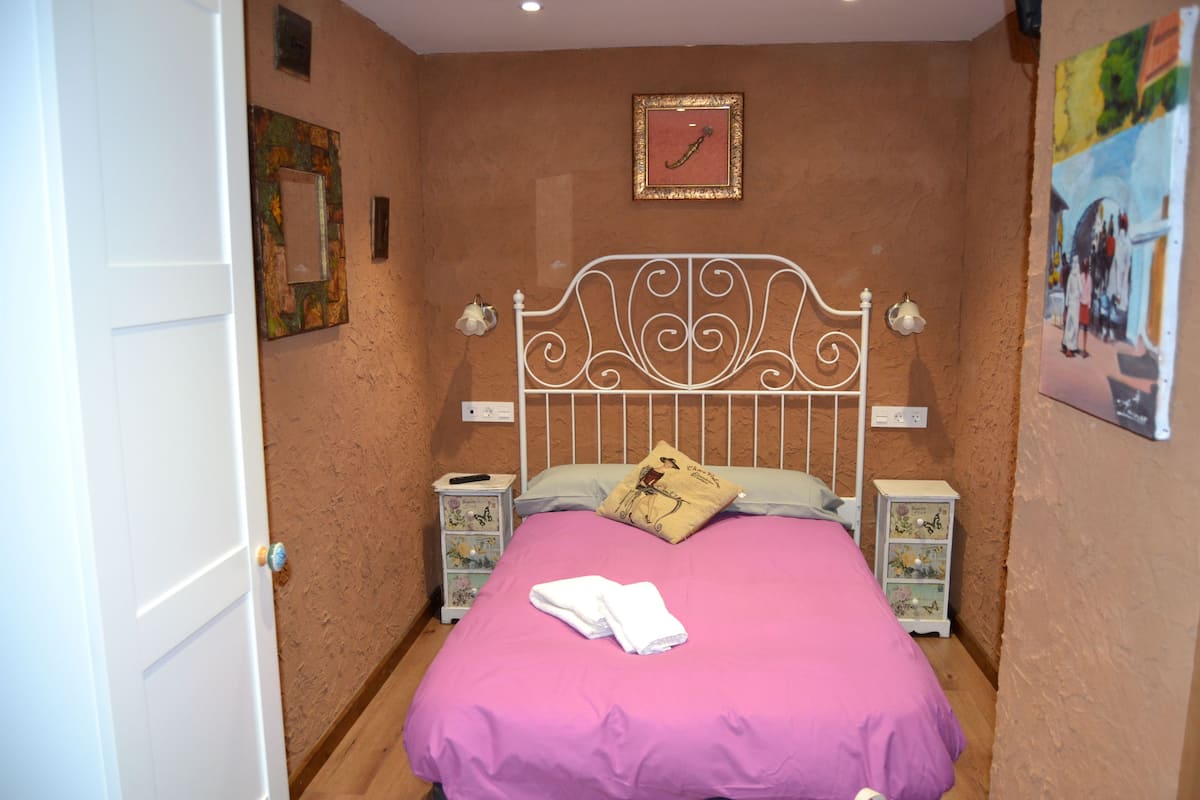 A bedroom with a bed, white headboard, and two bedside tables with lamps.