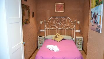 A bedroom with a bed, white headboard, and two bedside tables with lamps.