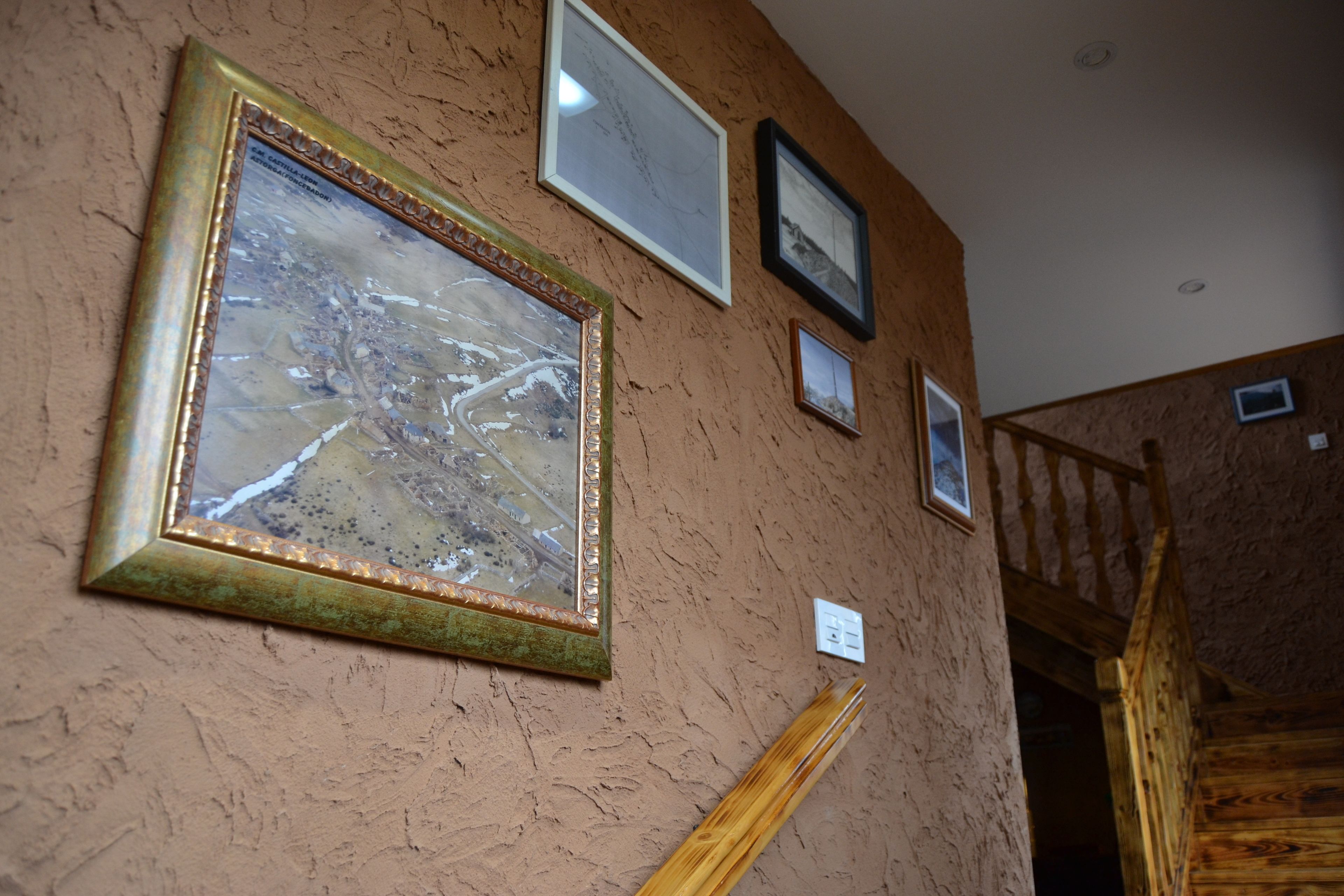 Ein Zimmer mit strukturierter Wand, einem großen gerahmten Bild und einer Holztreppe.
