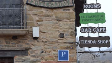 Een stenen gebouw met een bord waarop 'Hostería Rooms' en 'El Trásgu de Foncebadón Bar-Cafe' staat.
