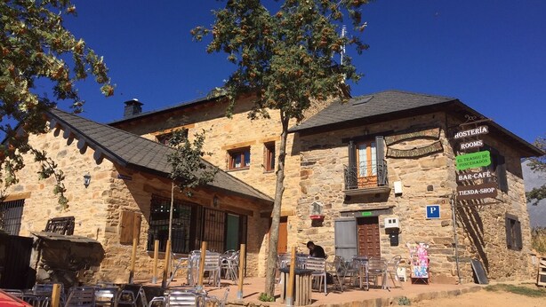 A stone building with a sign indicating rooms, bar-cafe, and shop. - El Trasgu de Foncebadón (Santa Colomba de Somoza)