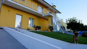 A yellow building with a white balcony, a staircase, and a dog on the grass. - 2 bedroom house with modern furniture1 suite with toillet, terrace /25 km Porto (Cedofeita)