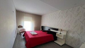 A hotel room with a bed, a desk, a chair, and a window with curtains. - 2 bedroom house with modern furniture1 suite with toillet, terrace /25 km Porto (Cedofeita)