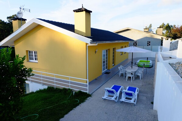A yellow house with a patio, outdoor seating, and a green inflatable pool.