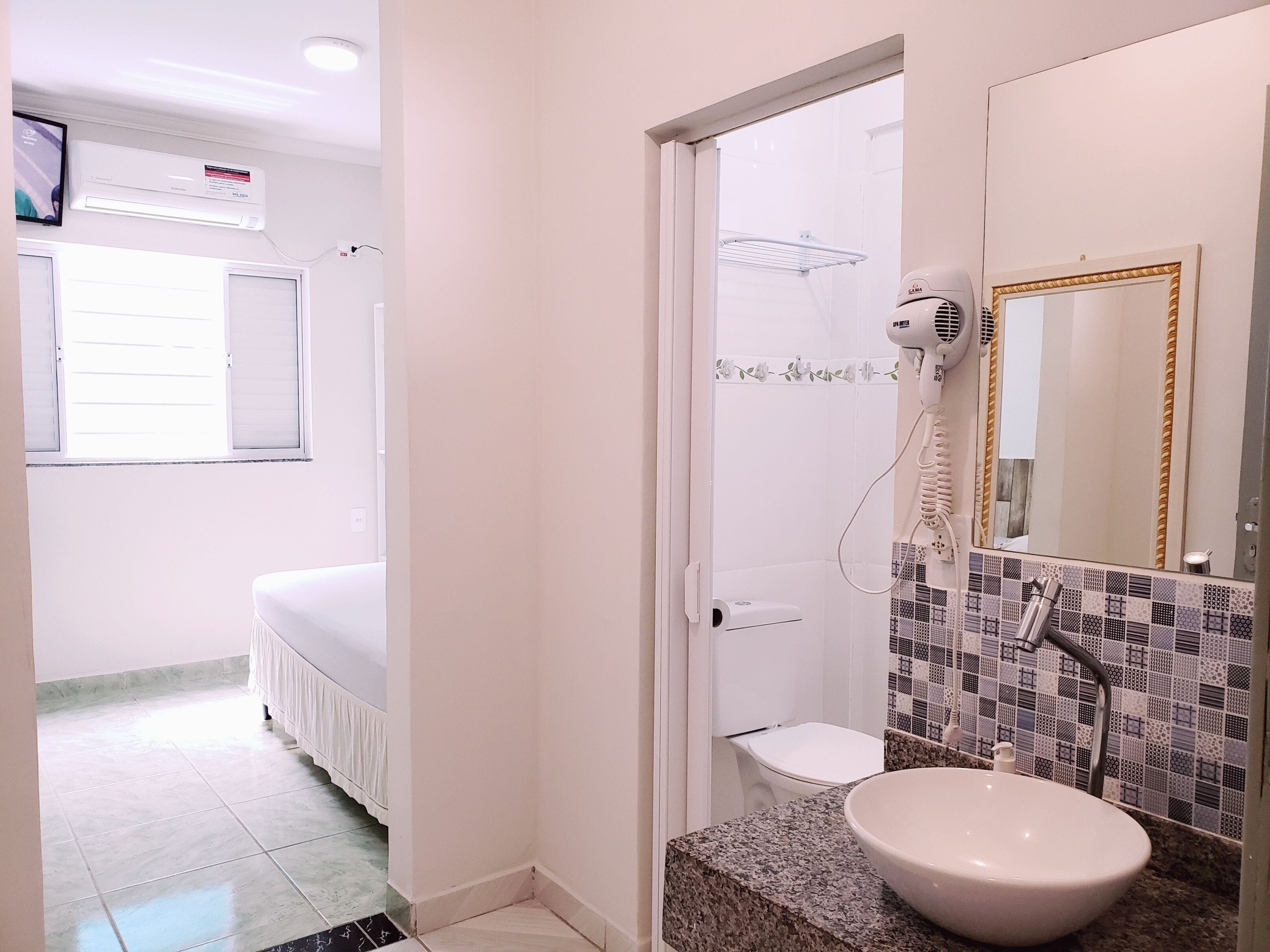 A bathroom with a sink, mirror, and shower.