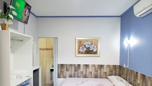 Une chambre à coucher comprenant un lit, une armoire, un téléviseur, un tableau encadré et un appareil de climatisation.