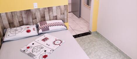 A hotel room with a bed, two pillows, a wooden headboard, a mirror, and a door.