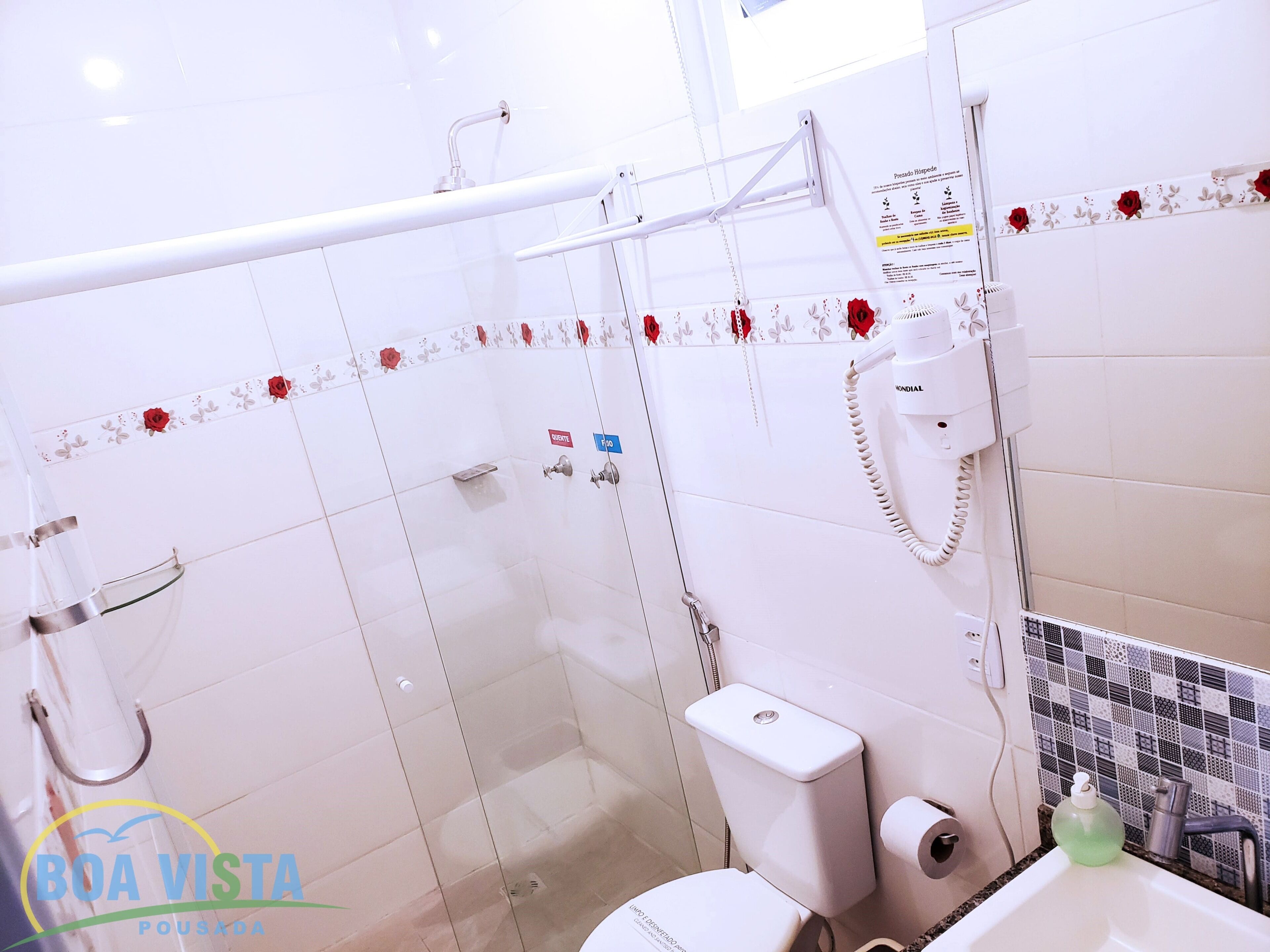 A bathroom with a glass shower enclosure, a toilet, a sink with a soap dispenser, and a hand dryer.