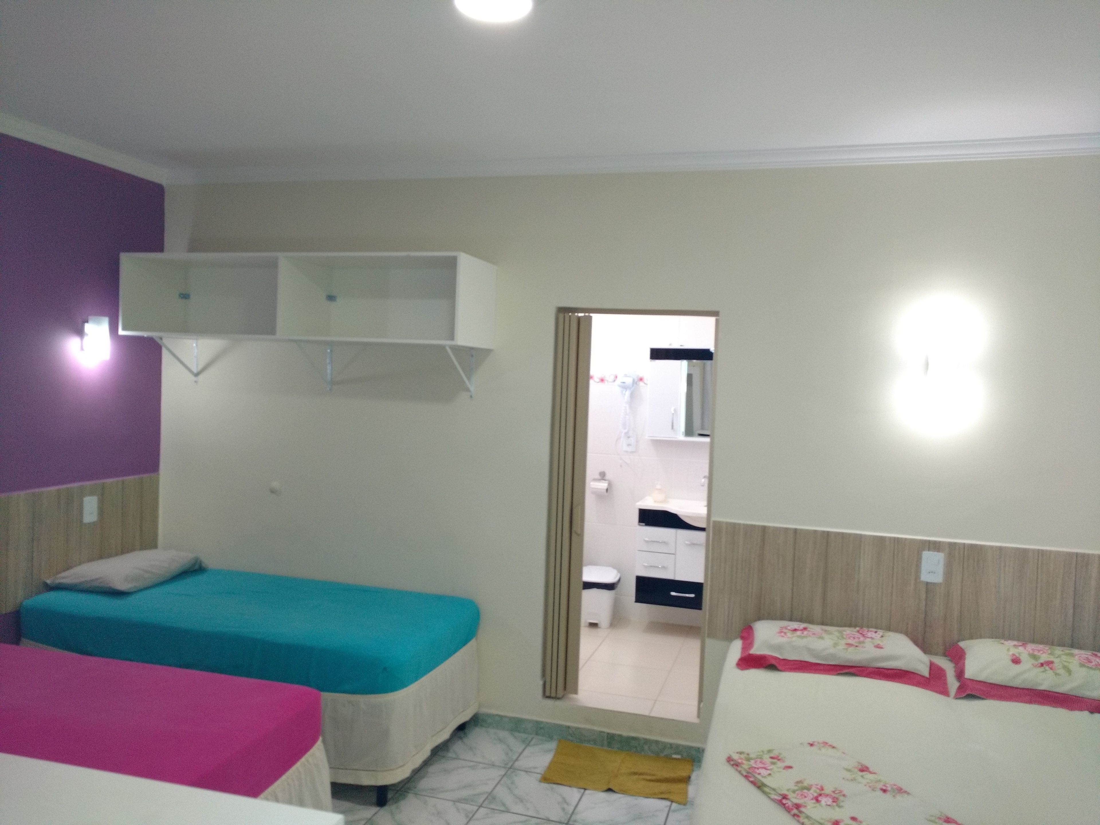 A bedroom with two beds, a wardrobe, and a bathroom visible through an open door.