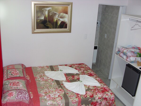 A hotel room with a bed, a shower, and a TV.