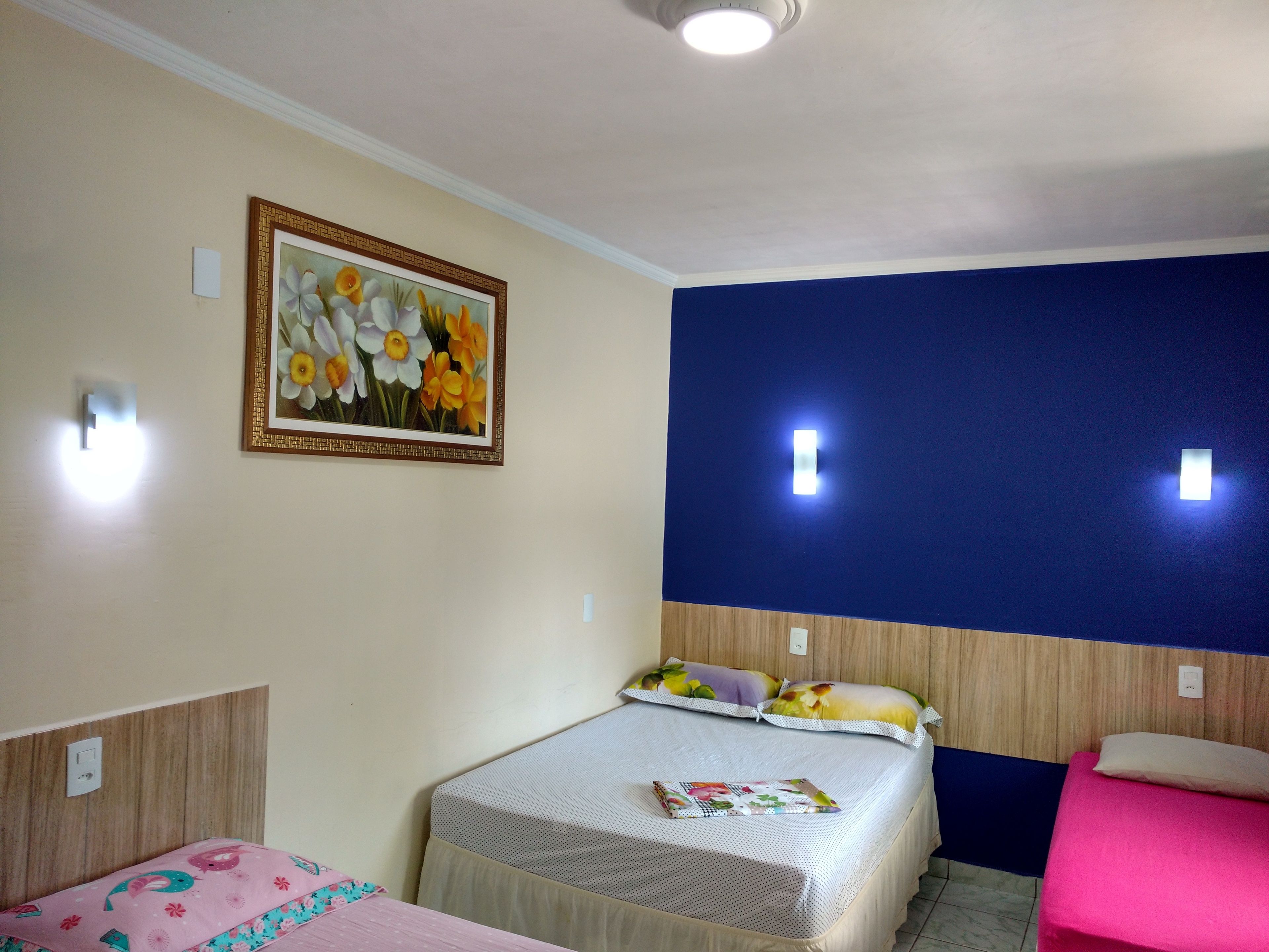 A hotel room with a bed, a chair, and a painting on the wall.