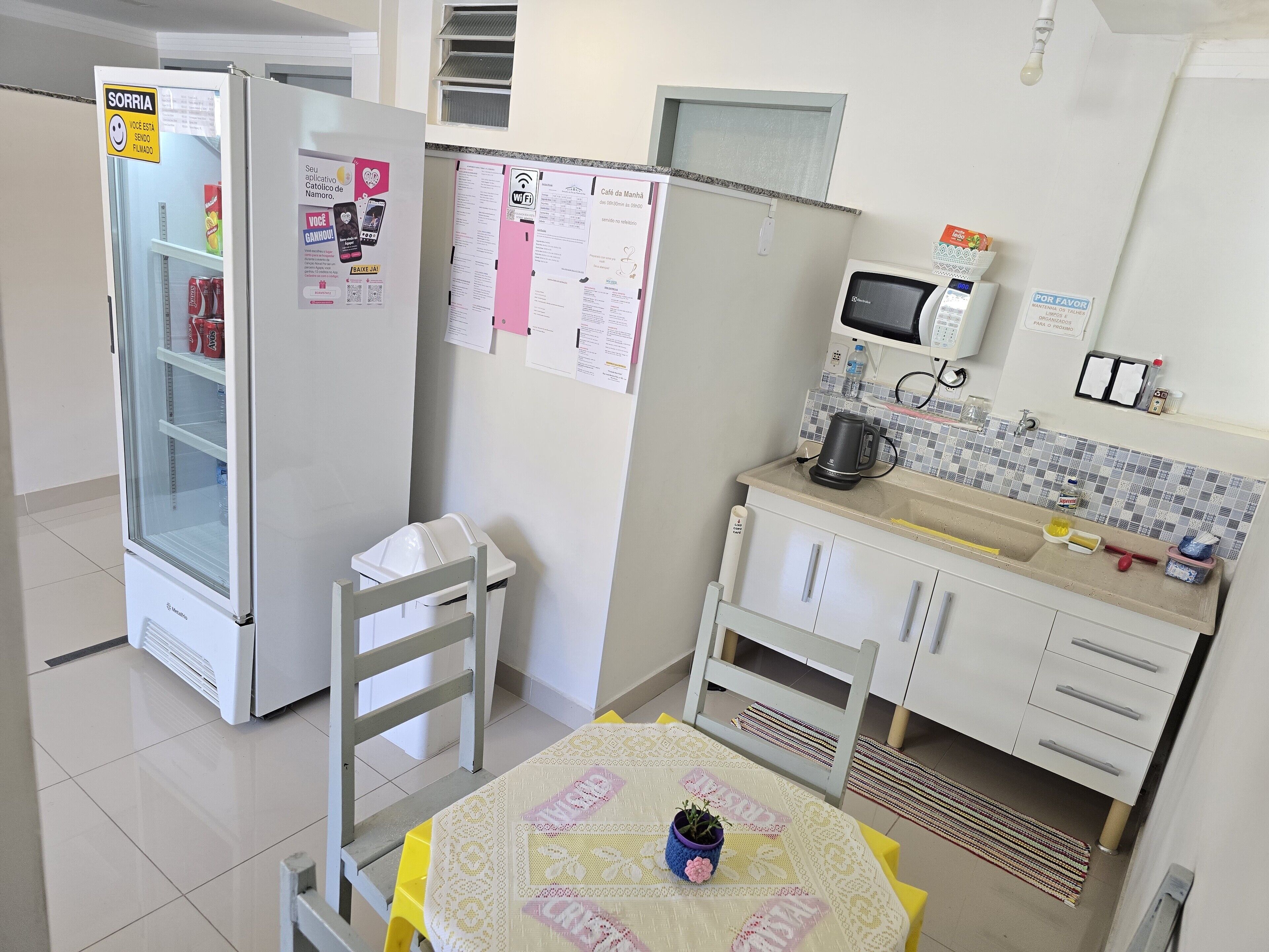A compact kitchenette with a refrigerator, microwave, and a small sink area.
