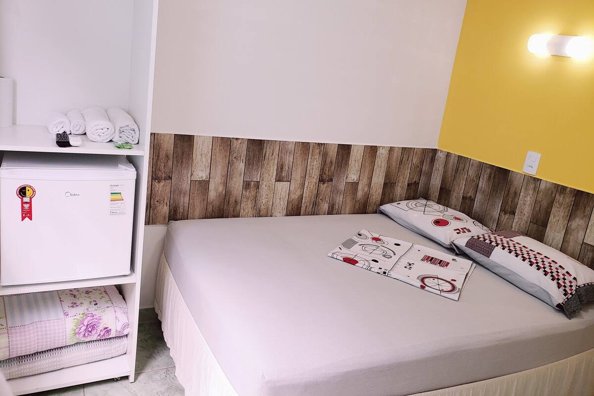 Ein Hotelzimmer mit einem Bett, einem weißen Schrank und einem kleinen Kühlschrank.