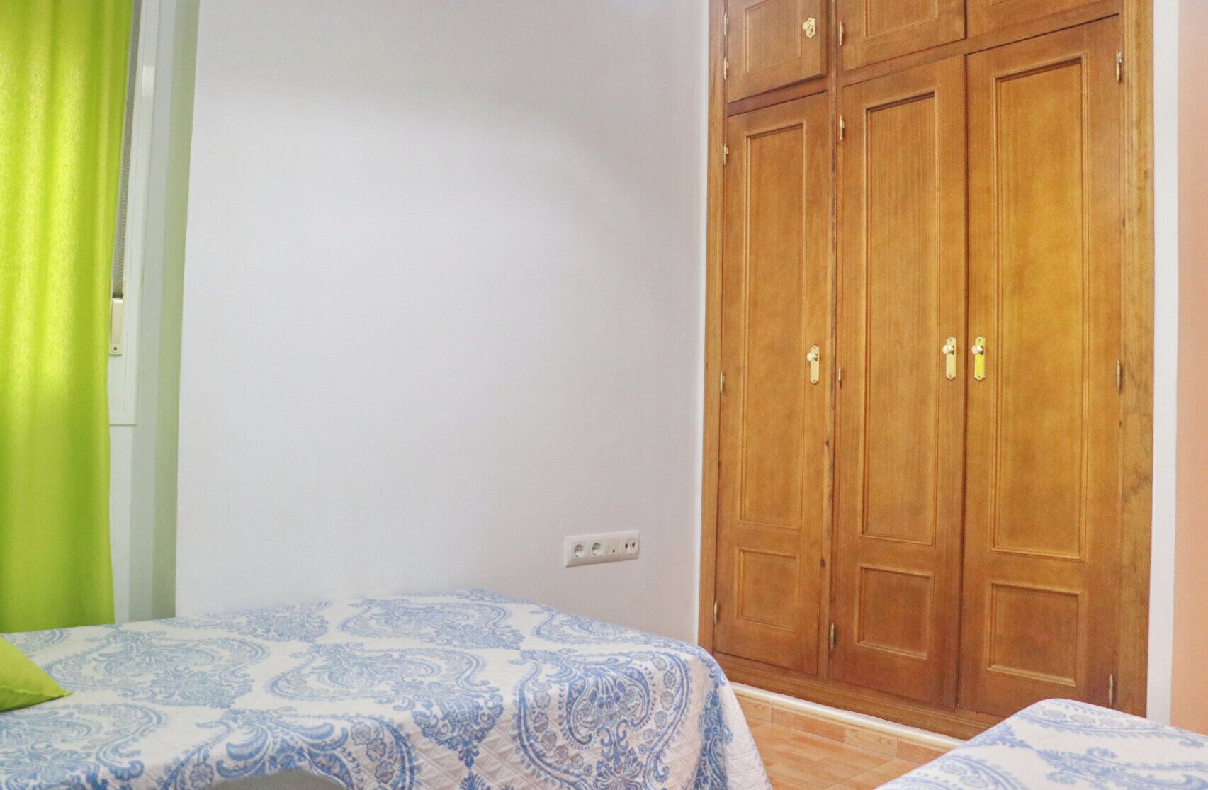 A bedroom with a bed, a wardrobe, and a green curtain.