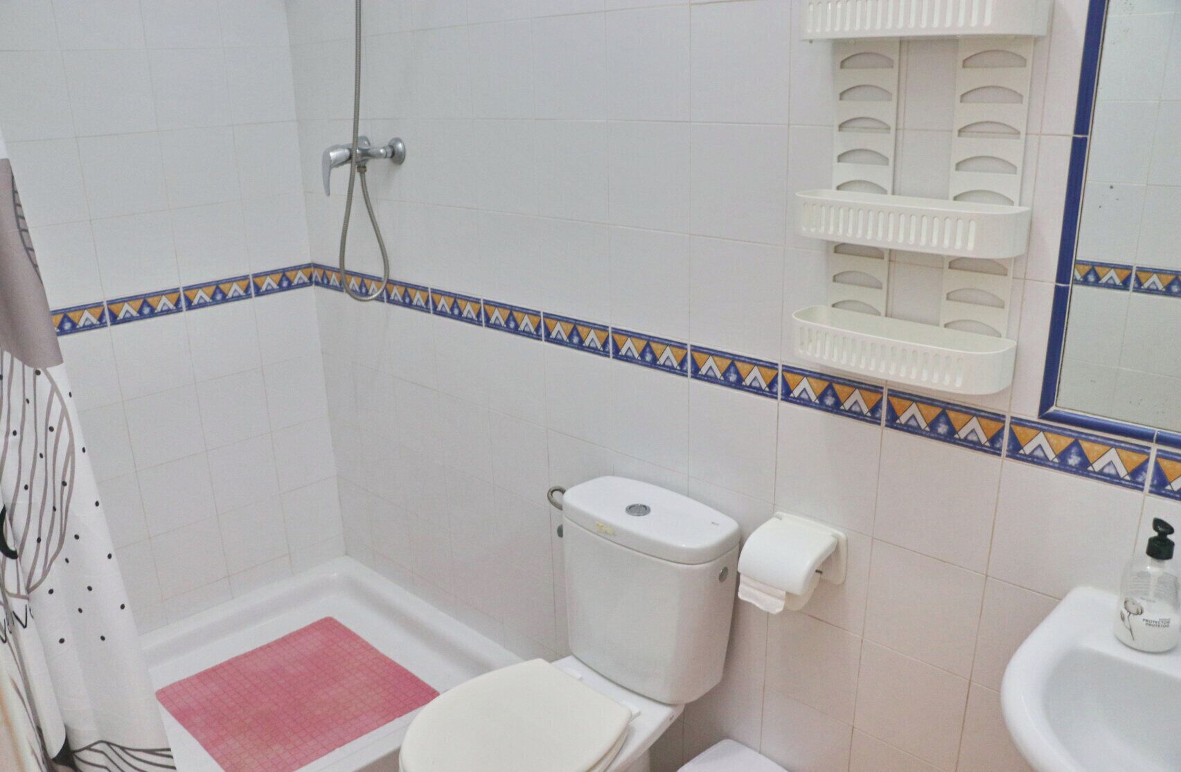 Un baño con ducha, inodoro y lavabo.