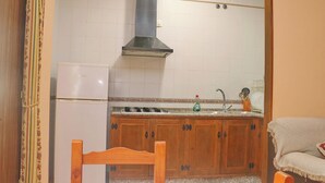 A kitchen with white tiled walls, a stainless steel range hood, wooden cabinets, a white refrigerator, and a sink with dishware. - Two bedroom apartment close to beaches (Conil de la Frontera)