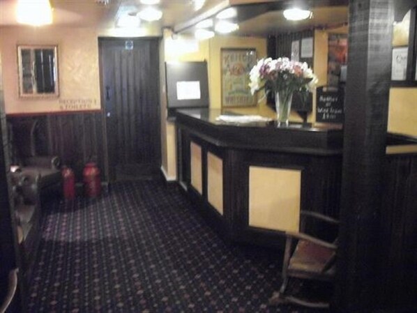 A reception area with a check-in counter, a seating area with chairs, and a patterned carpet.