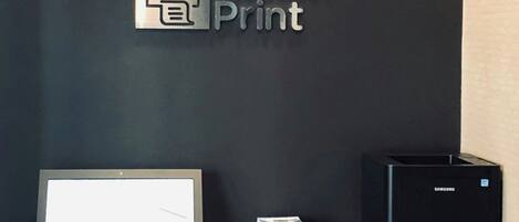 Un comptoir d’accueil équipé d’un ordinateur, d’une imprimante et d’une pancarte indiquant « Impression rapide ».