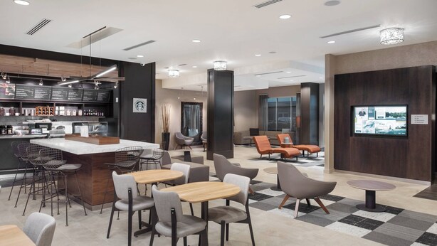 A modern cafe with a bar area, seating, and a large screen displaying content.