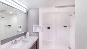 A modern bathroom with a large mirror, a sink, and a shower area.