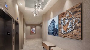 A hallway with elevators, benches, and artwork on the walls. - Courtyard by Marriott Baton Rouge Downtown (Baton Rouge)
