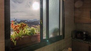 Een keuken met een raam dat uitkijkt op een tuin en op verre bergen.