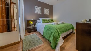 Een slaapkamer met een bed, nachtkastje, bureau, plafondventilator en een wand met twee decoratieve borden.