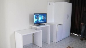 A compact living space with a television on a small table, a white refrigerator, and a white cabinet. - Hotel Nika (Vlorë)