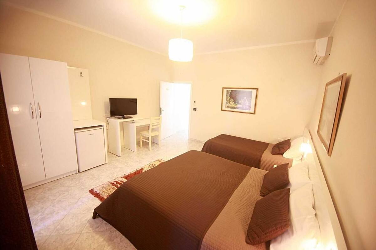 A hotel room with two beds, a desk, a chair, a television, and a wardrobe.