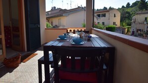 A balcony with a table set for two, a brown handbag, and a door with shutters. - Holiday Apartment Ciliegio, Marina di Campo convenient for the beach and center. (Marina di Campo)