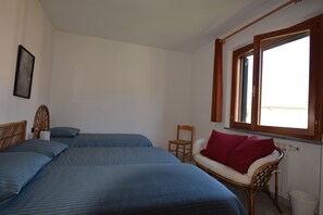 Ein Schlafzimmer mit zwei Betten, einem Sessel, einem Fenster und einer Heizung.